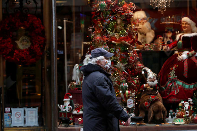 An elderly man wearing a protective face mask walks in front of a Christmas store display in downtown Budapest, after Hungarian government imposed a nationwide lockdown to contain the spread of the coronavirus disease (COVID-19)
