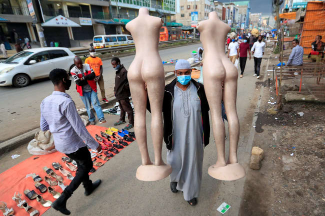A masked-trader carriers two female-form mannequins as he closes his business ahead of the lockdown resulting from the COVID-19 pandemic in Nairobi, Kenya.