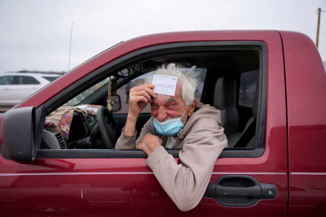 poses for a portrait with his vaccination card after receiving his coronavirus disease (COVID-19) vaccine at a rural vaccination site in Columbus, New Mexico, U.S., April 16, 2021.