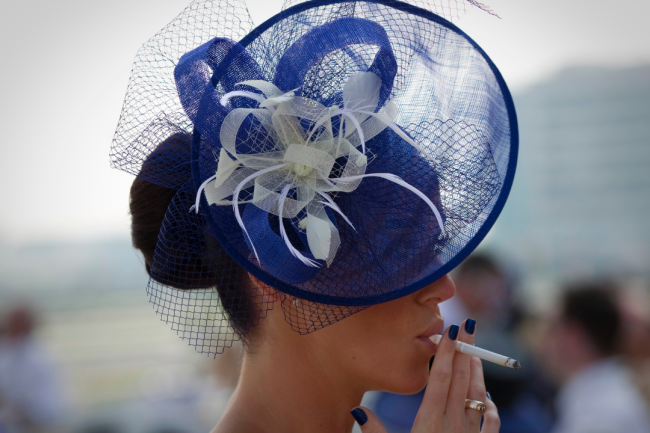 A spectator smokes a cigarette as she waits for the start of the Dubai World Cup racehorse at Meydan Racecourse in Dubai, United Arab Emirates on March 29, 2014. REUTERS/Caren Firouz