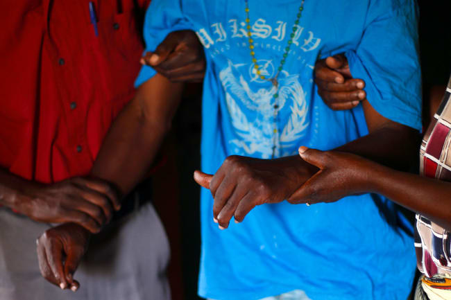 A person with HIV/AIDS is helped to his bedroom by caregivers from a community home-based care team visiting him at his home in Matero township on the outskirts of Lusaka, Zambia on April 17, 2012. The picture shows the torso of a man wearing a loose-fitting light blue shirt being helped by two other people. REUTERS/Darrin Zammit Lupi 
