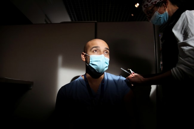 Physician Alister Martin received one of the first doses of the Pfizer-BioNTech coronavirus disease (COVID-19) vaccine from RN Jennifer Lisciotti at Massachusetts General Hospital in Boston, Massachusetts, U.S., December 16, 2020.