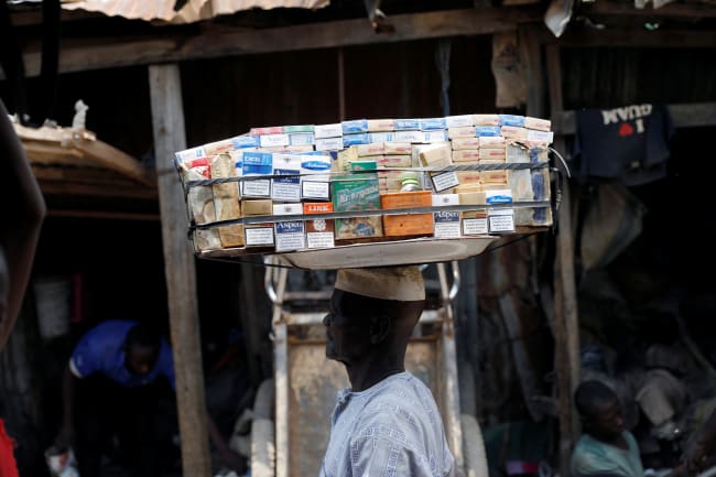 A man selling packets of cigarettes walks through a street, in the old district of Kano, Nigeria, on August 24, 2017.