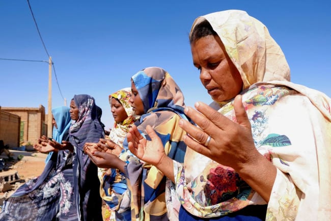 Women pray in front of a house struck by a drone, in El-Obeid, North Kordofan state, Sudan, on January 12, 2026.