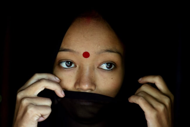 A woman living with HIV/AIDS stands in her hut in the northeastern Indian city of Siliguri on July 23, 2005. The photo shows the woman with a wrap covering her mouth. REUTERS/Rupak De Chowdhuri