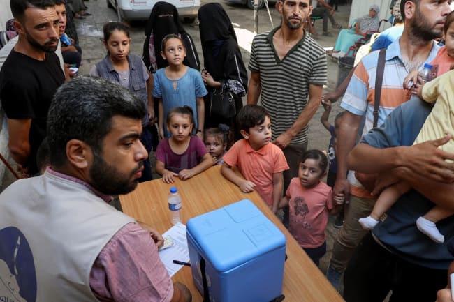 Palestinian children, accompanied by parents, wait to be vaccinated against polio.