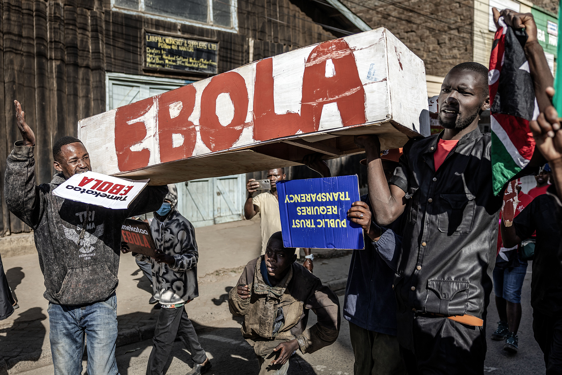 Protesters carry signs and a mock coffin on the street that reads, "EBOLA" in protest of the U.S.-built quarantine center in Kenya.