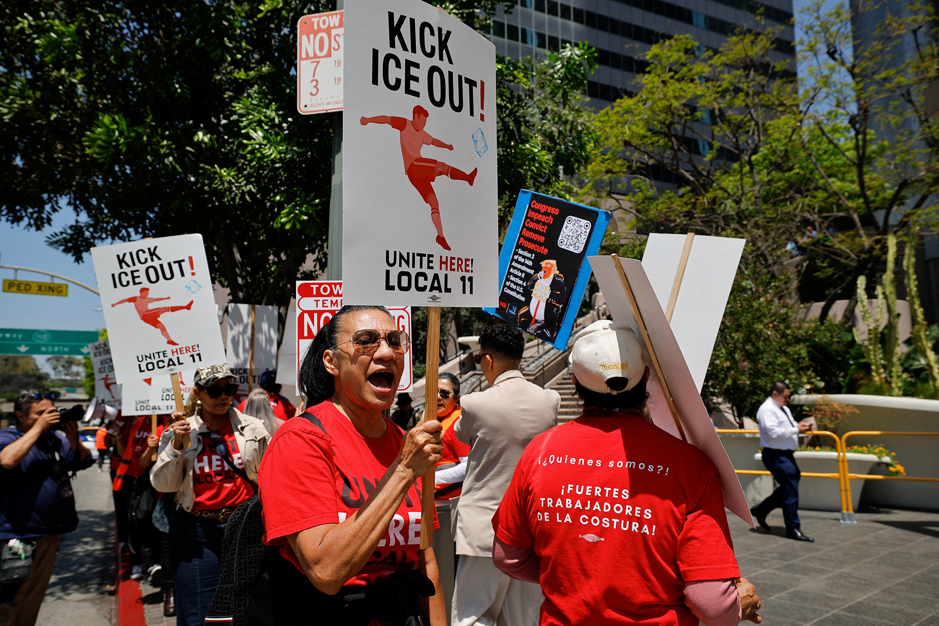 Staff marches outside Sofi Stadium in Los Angeles in red t-shirts, holding signs in protest of U.S. immigration forces at the World Cup.