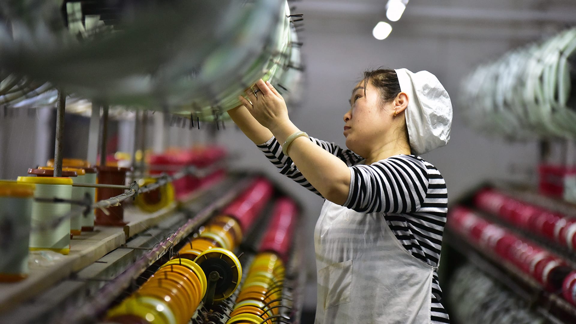<p> A silk textile worker stands on the production line of a factory in Fuyang, China.</p>
