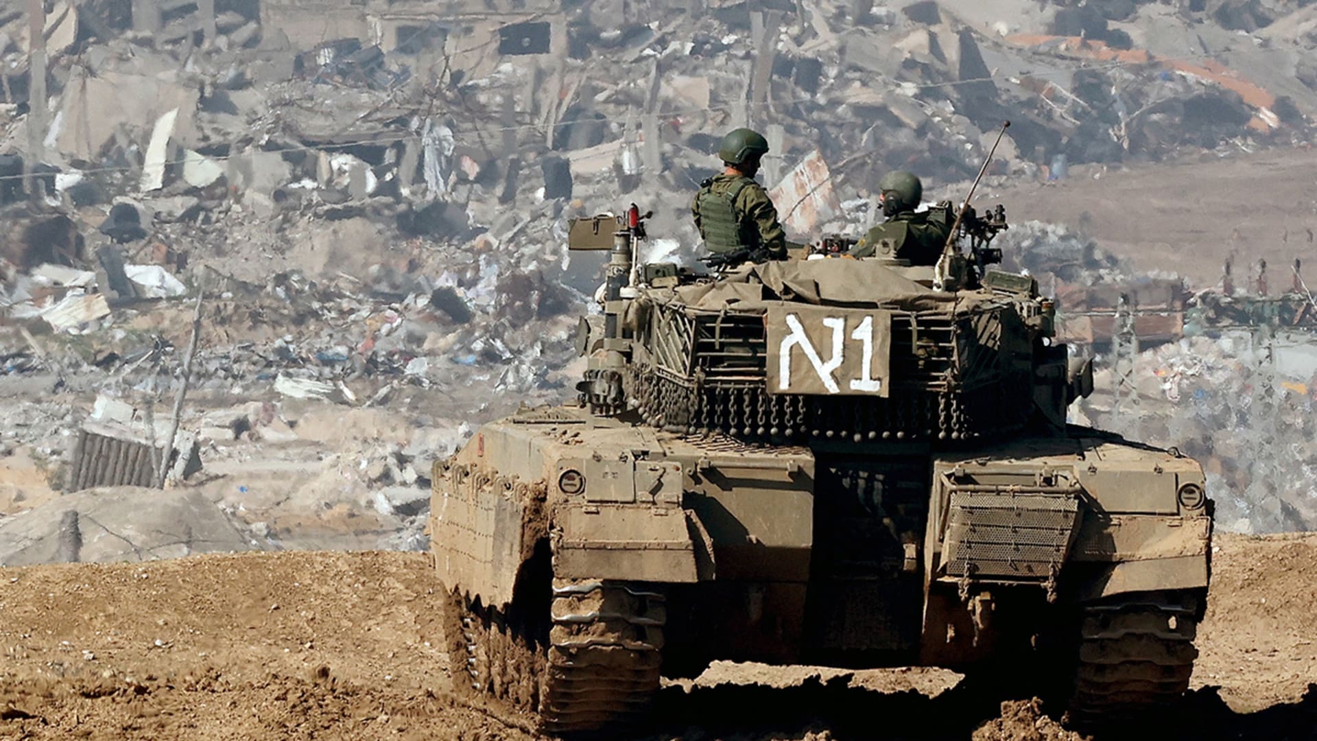 <p>An Israeli tank drives past damaged buildings near the Gaza Strip border in southern Israel on January 19, 2024.</p>

