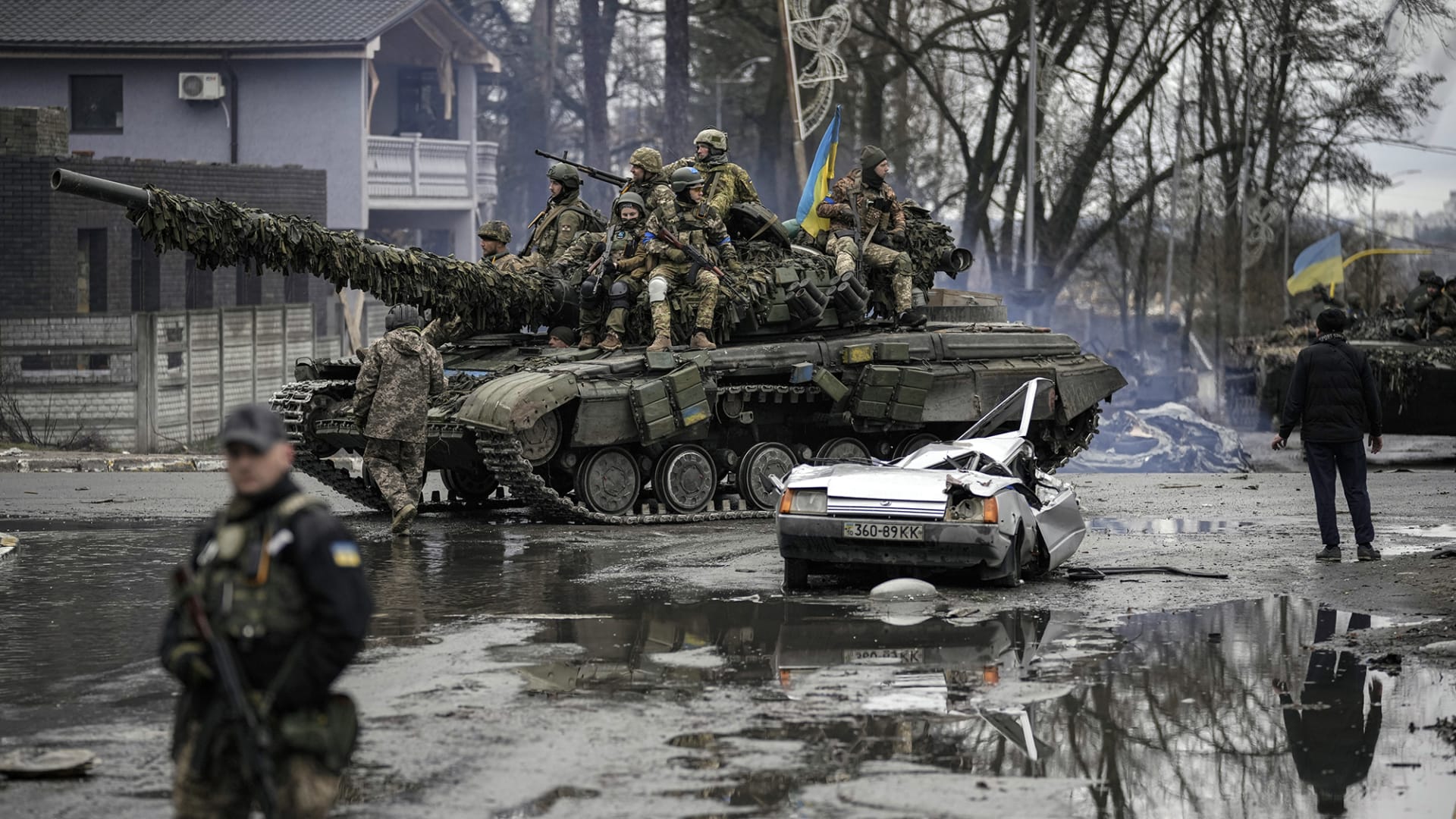 <p>Ukrainian servicemen ride a tank next to a civilian vehicle destroyed during fighting between Russian and Ukrainian forces outside Kyiv, Ukraine, on April 2, 2022.</p>
