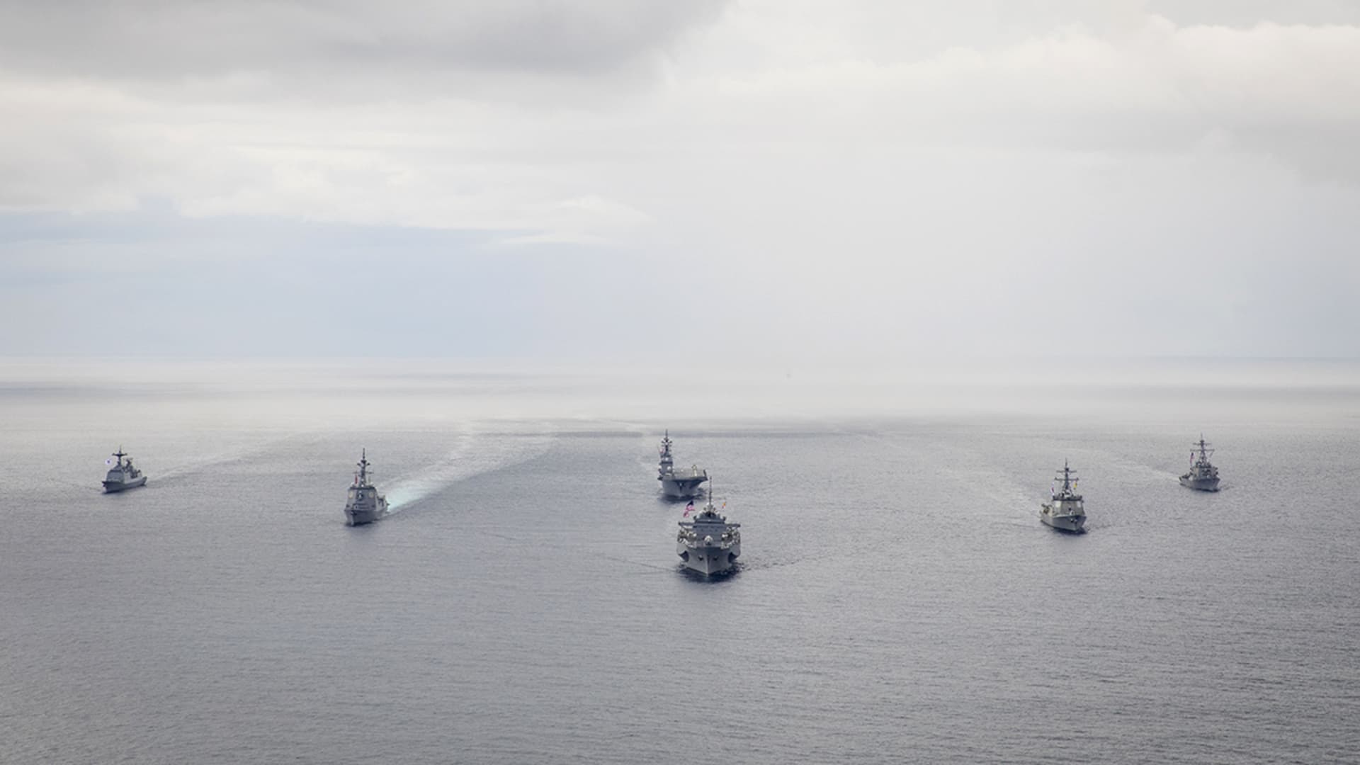 Several U.S. naval vessels cruising on open water.