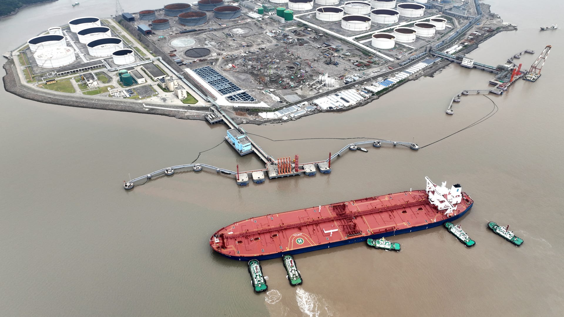 An aerial view shows tugboats helping a crude oil tanker to berth at an oil terminal, off Waidiao Island in Zhoushan, Zhejiang province, China July 18, 2022. cnsphoto via REUTERS