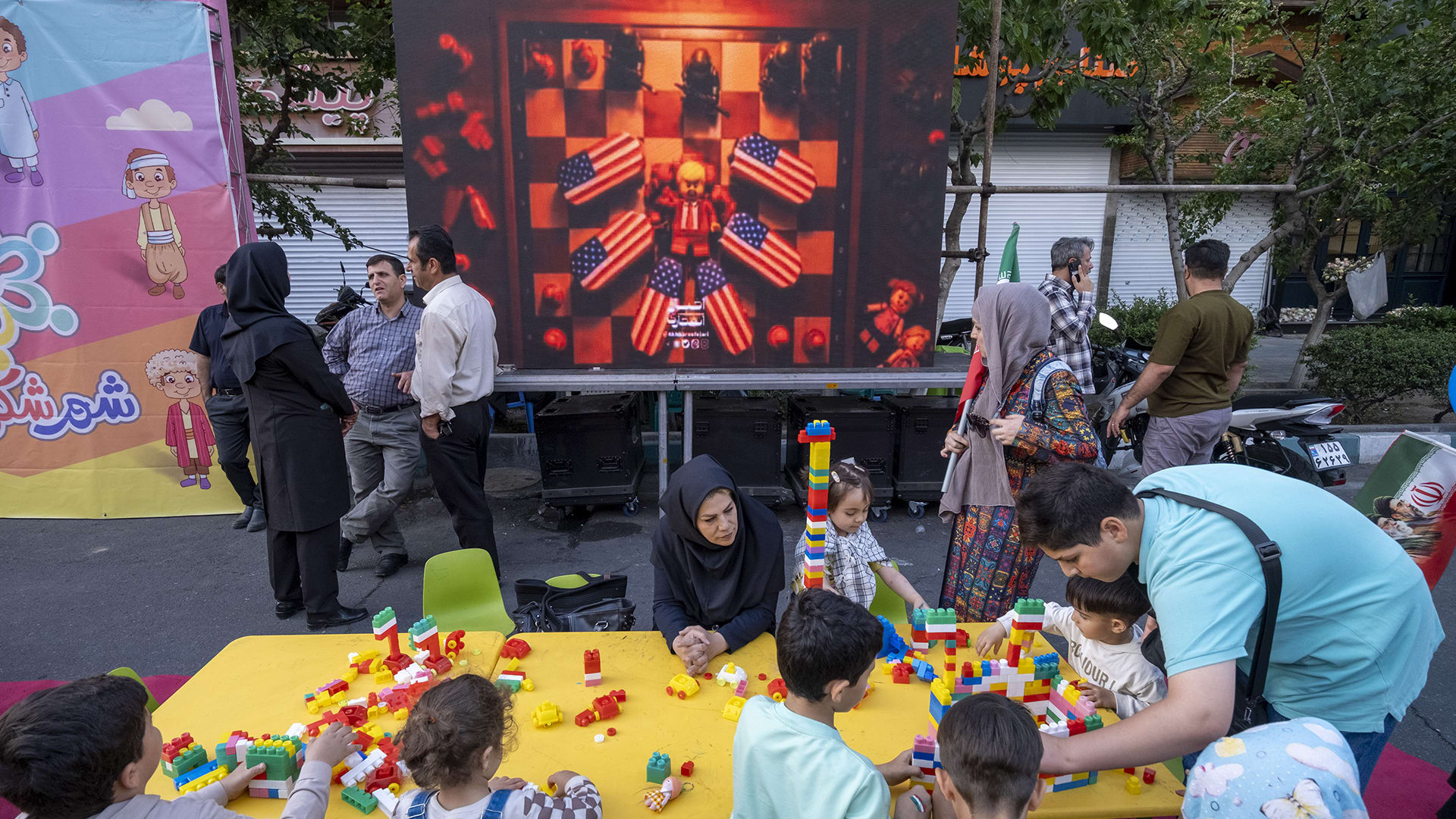 Iranian children play as an animation featuring an effigy of U.S. President Donald Trump and coffins of American soldiers is displayed during a state-run religious rally in downtown Tehran, Iran, on April 29, 2026.