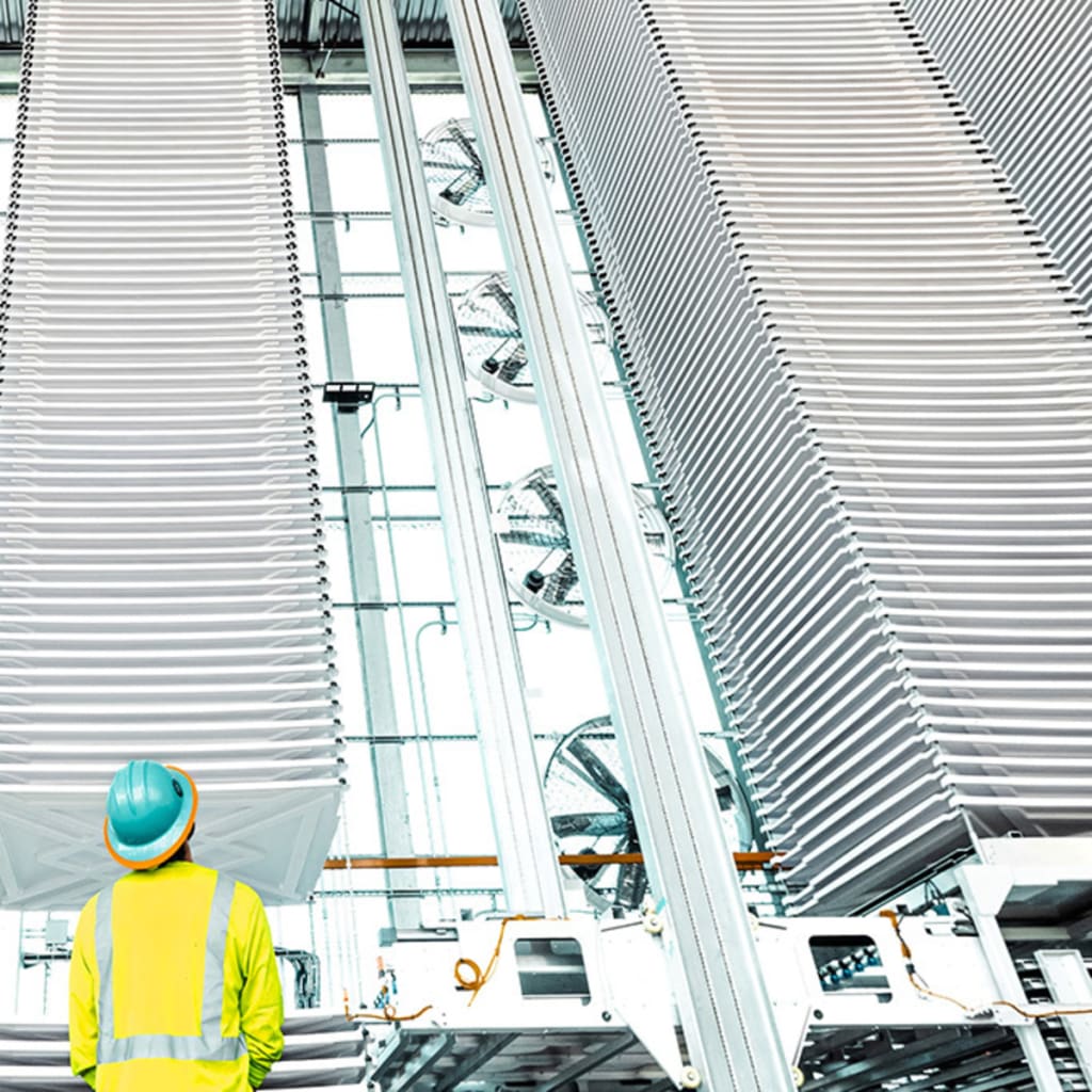 <p>A person looks at stacks of trays holding treated limestone, used to absorb CO2 form the air, at a plant in Tracy, California,.</p>