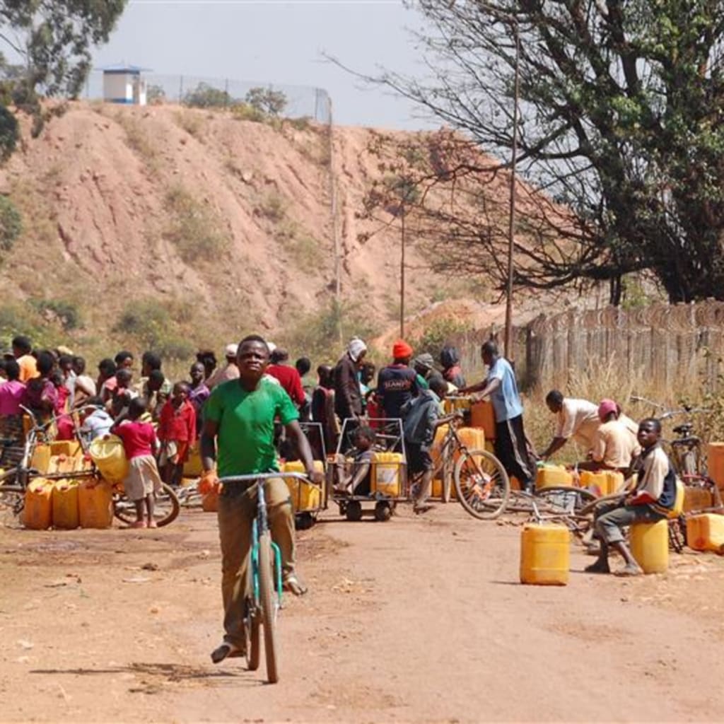 <p>People fetch water outside a cobalt and copper mine run by Sicomines in Kolwezi, Democratic Republic of Congo, on May 30, 2015.</p>
