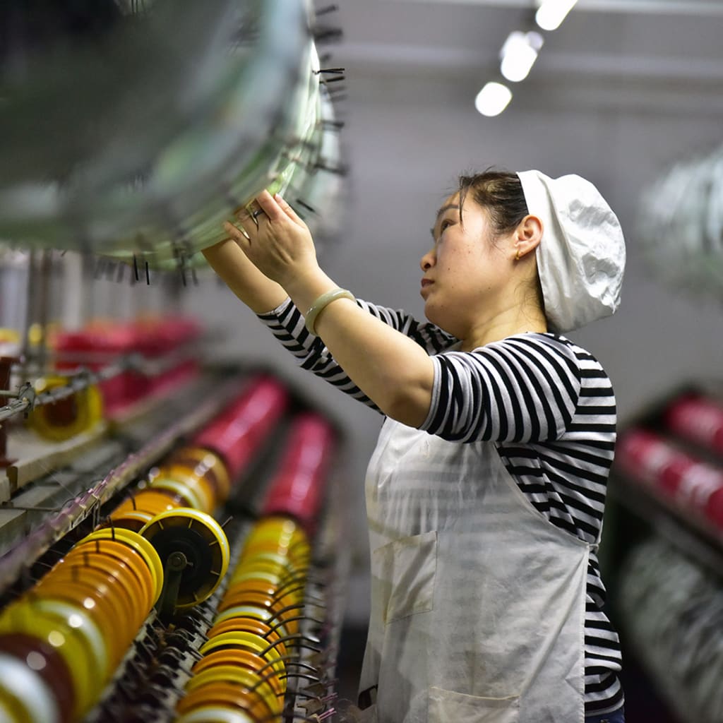<p> A silk textile worker stands on the production line of a factory in Fuyang, China.</p>
