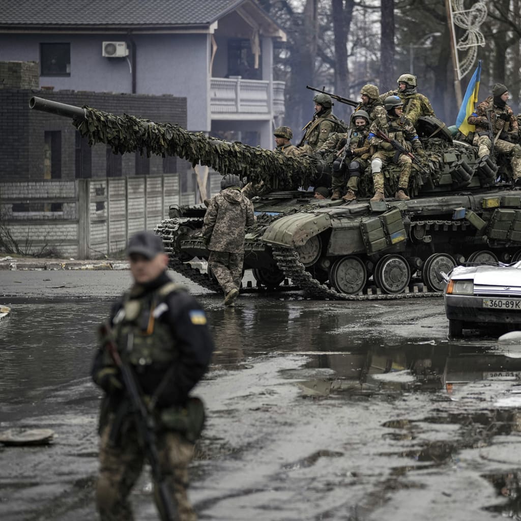 <p>Ukrainian servicemen ride a tank next to a civilian vehicle destroyed during fighting between Russian and Ukrainian forces outside Kyiv, Ukraine, on April 2, 2022.</p>
