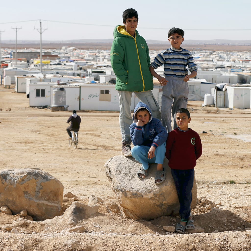 <p>Syrian refugee children standing on a rock in Al Zaatari refugee camp in the Jordanian city of Mafraq.</p>
