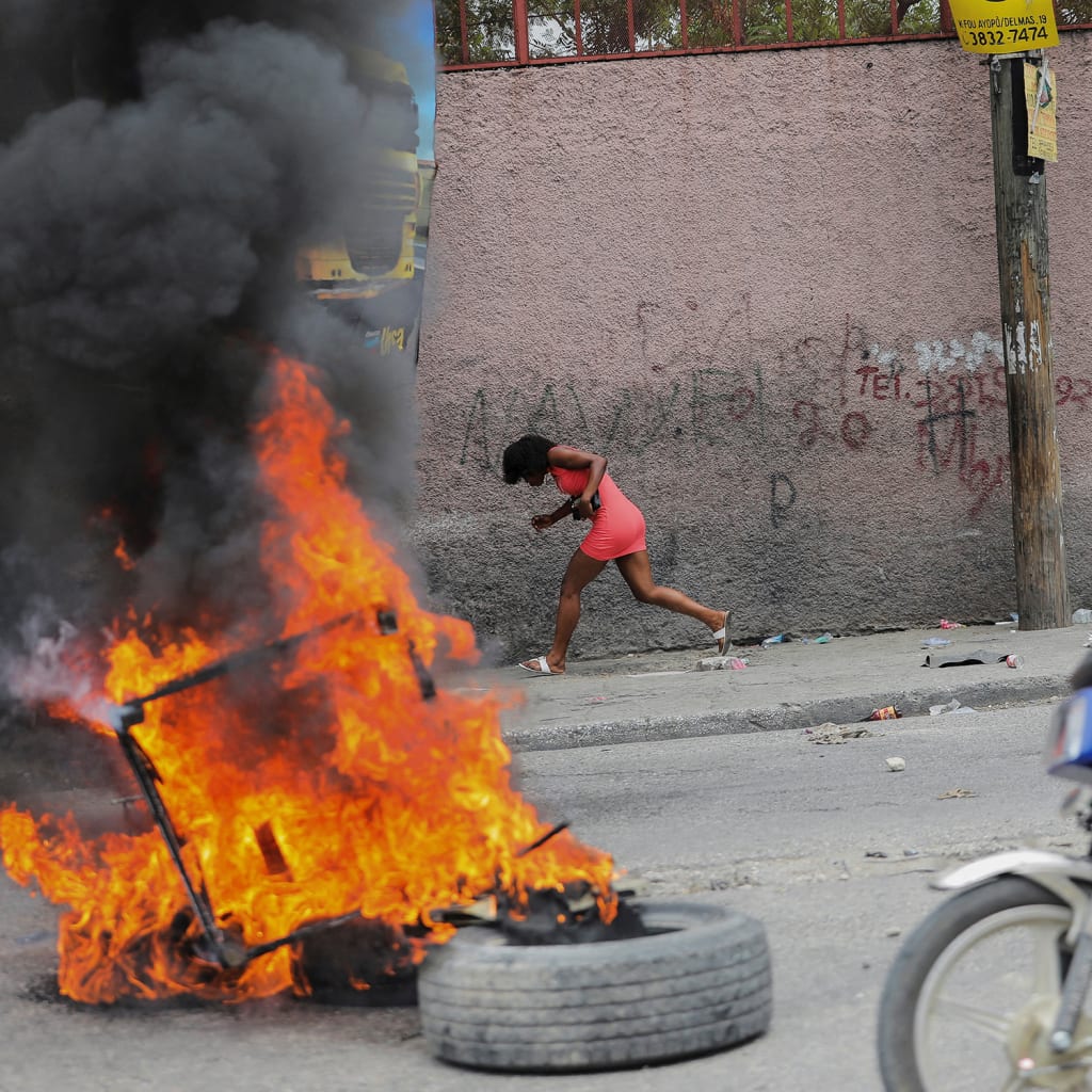 <p>A woman runs past a burning barricade during a protest against growing fuel scarcity, soaring consumer prices, and crime in Port-au-Prince, Haiti, on August 29, 2022.</p>
