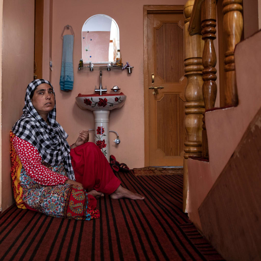 <p>A woman sits in the doorway of her home in Pulwama.</p>
