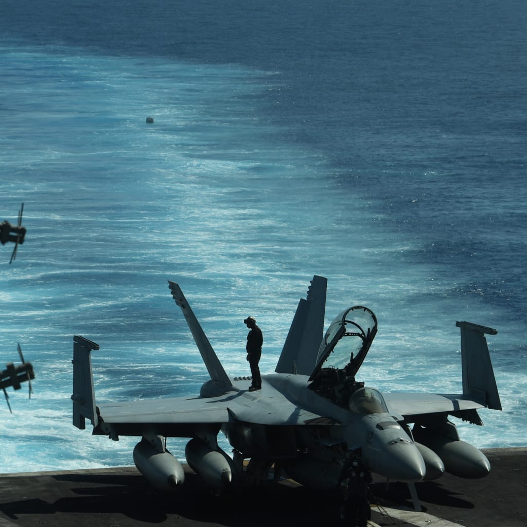 <p>A sailor inspects atop an FA-18 hornet fighter jet during a routine training aboard US aircraft carrier Theodore Roosevelt in the South China sea on April 10, 2018. </p>

