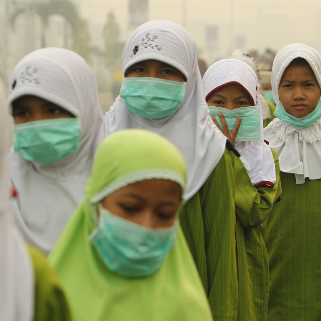 <p>Muslim students wearing masks walk in Dumai, on Indonesia’s Riau province in Sumatra, June 23, 2013.</p>

