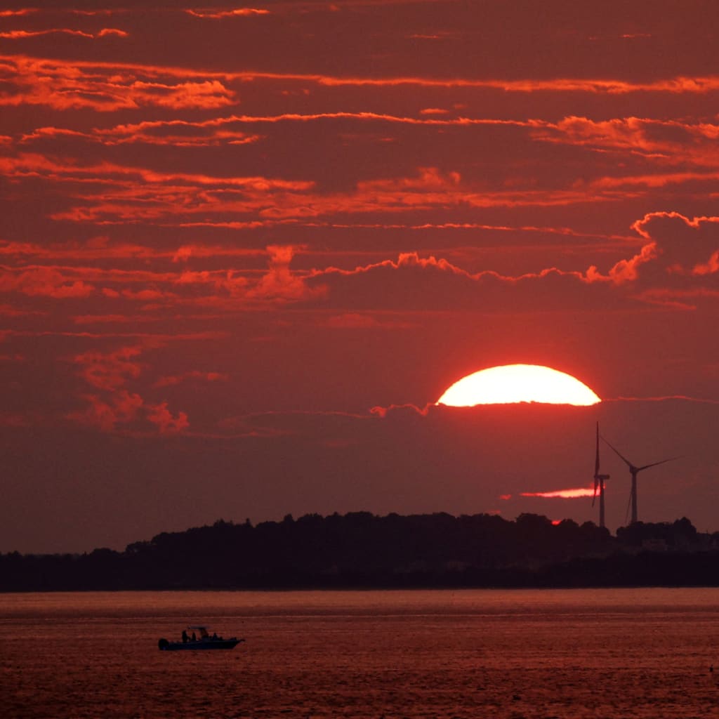 <p>The sun sets behind a pair of wind turbines in Newburyport, Massachusetts, U.S. on August 25, 2024.</p>
