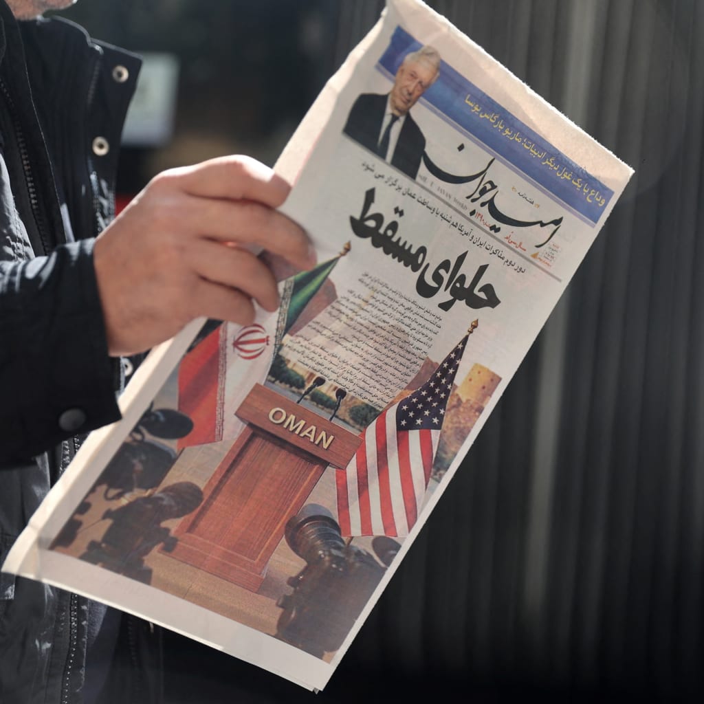 <p>An Iranian man holds a newspaper with a cover photo of Iran and U.S. flags on a street in Tehran, Iran, on April 19, 2025.</p>
