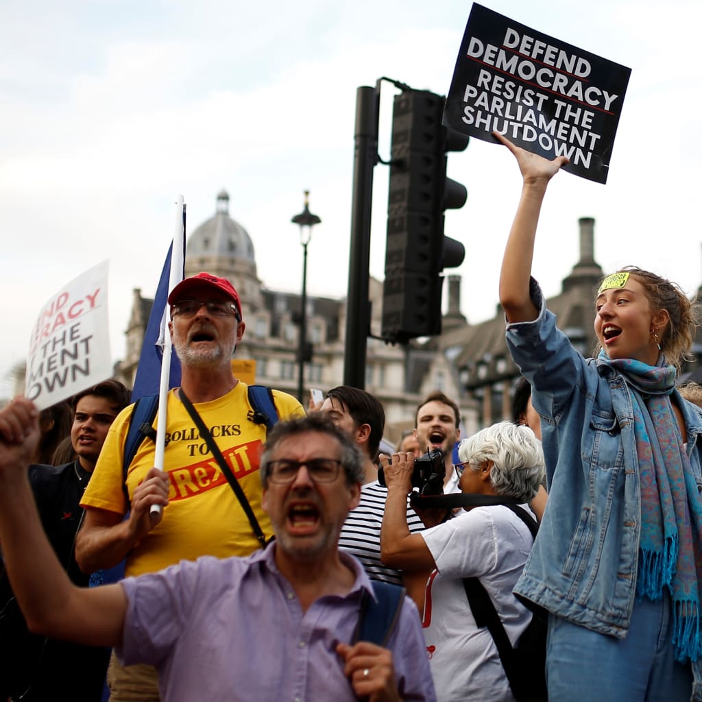 <p>Anti-Brexit protestors hold placards outside the Houses of Parliament in London</p>
