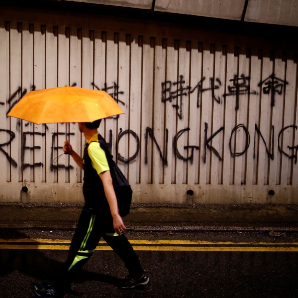 <p>A man walks past a graffiti during a march to demand democracy and political reforms in Hong Kong, China, August 18, 2019.</p>
