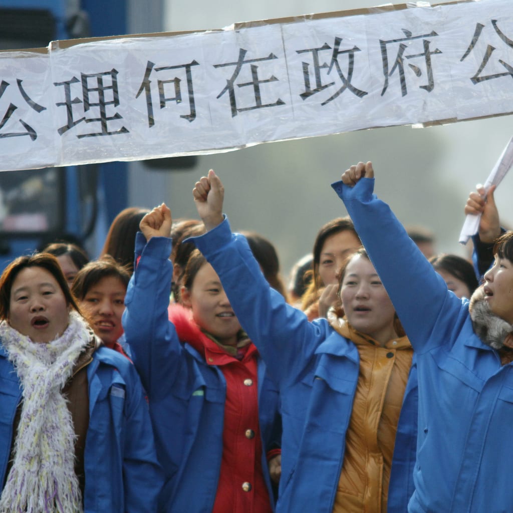 <p>Workers on strike blocking the entrance gate of Hi-P International factory yell slogans during a protest in Shanghai in December 2011.</p>