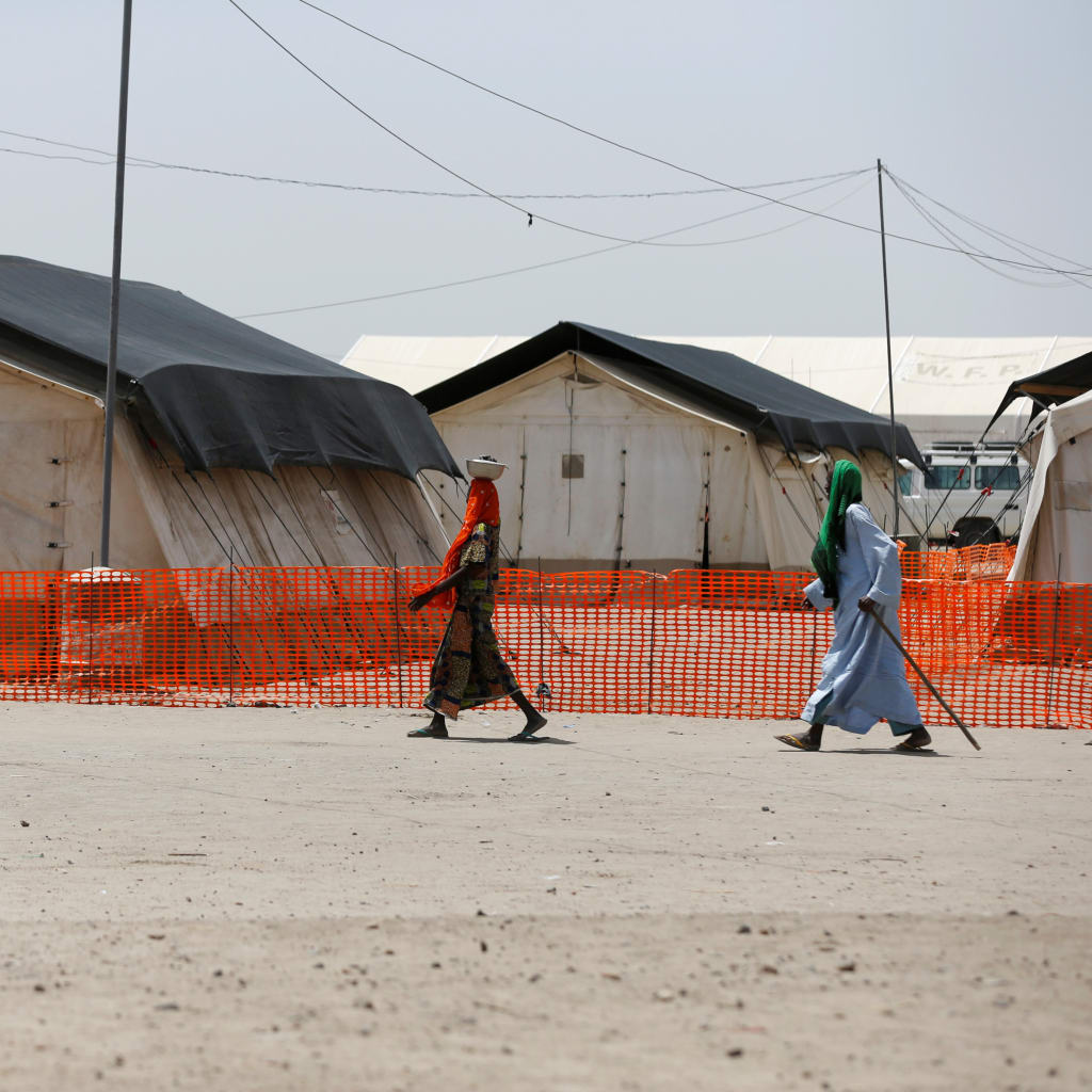 <p>A man and a woman walk past the World Food Program (WFP) tents at the Banki IDP camp, Borno, Nigeria, April 27, 2017.</p>
