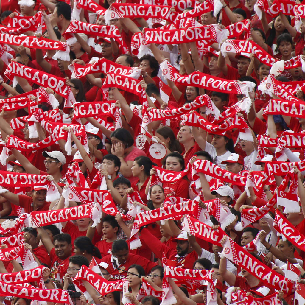 <p>People hold up Singapore banners during Singapore’s Golden Jubilee celebration parade for the nation’s 50th anniversary at Padang near the central business district on August 9, 2015.</p>

