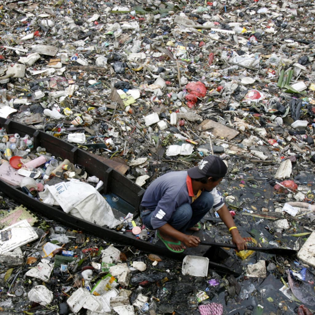 <p>A man sifts through a polluted river in Jakarta, Indonesia. </p>