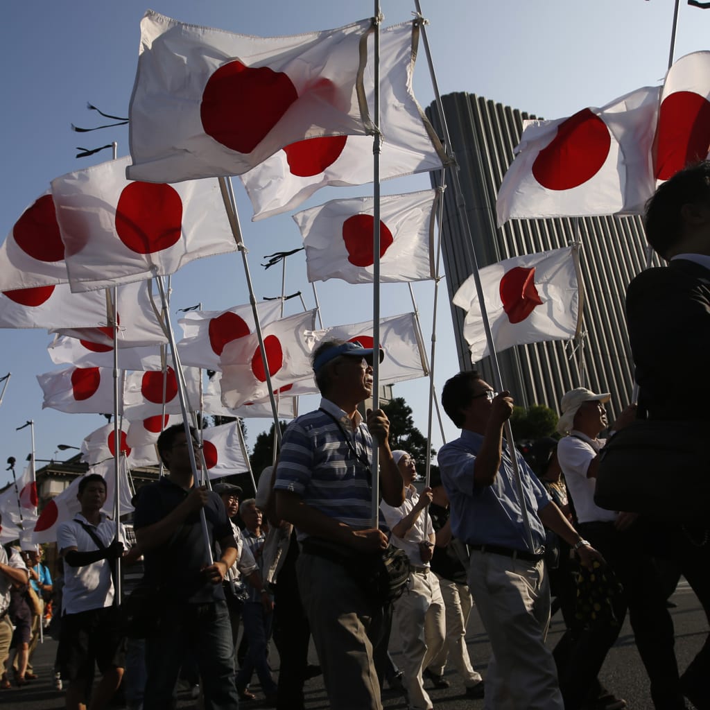 Members of the nationalist movement "Ganbare Nippon" march with Japanese national flags while paying tribute to the war dead near Yasukuni Shrine in Tokyo August 15, 2013.