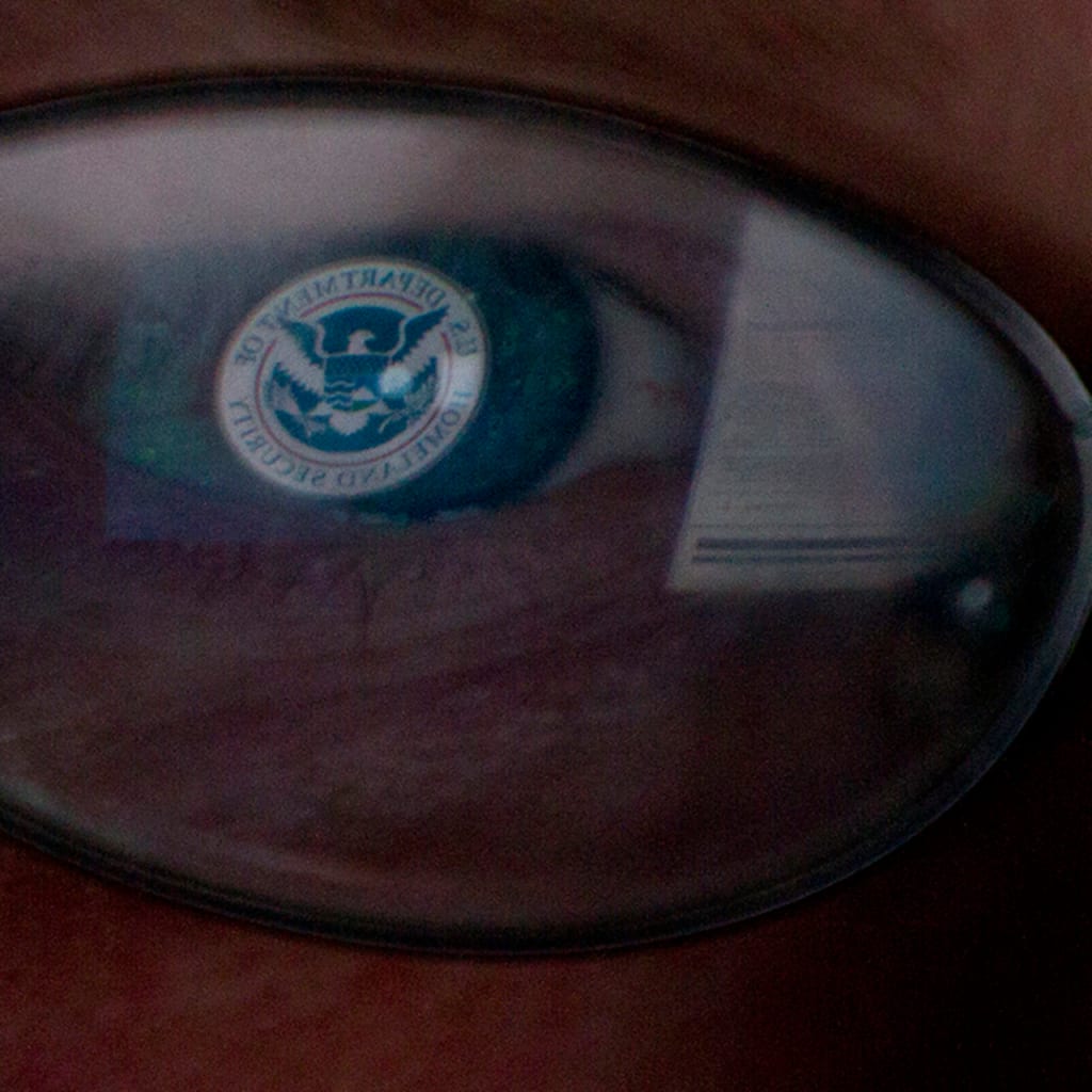 The logo of the U.S. Department of Homeland Security is reflected in the spectacles of an analyst working in a watch and warning center of a cyber security defense lab at the Idaho National Laboratory