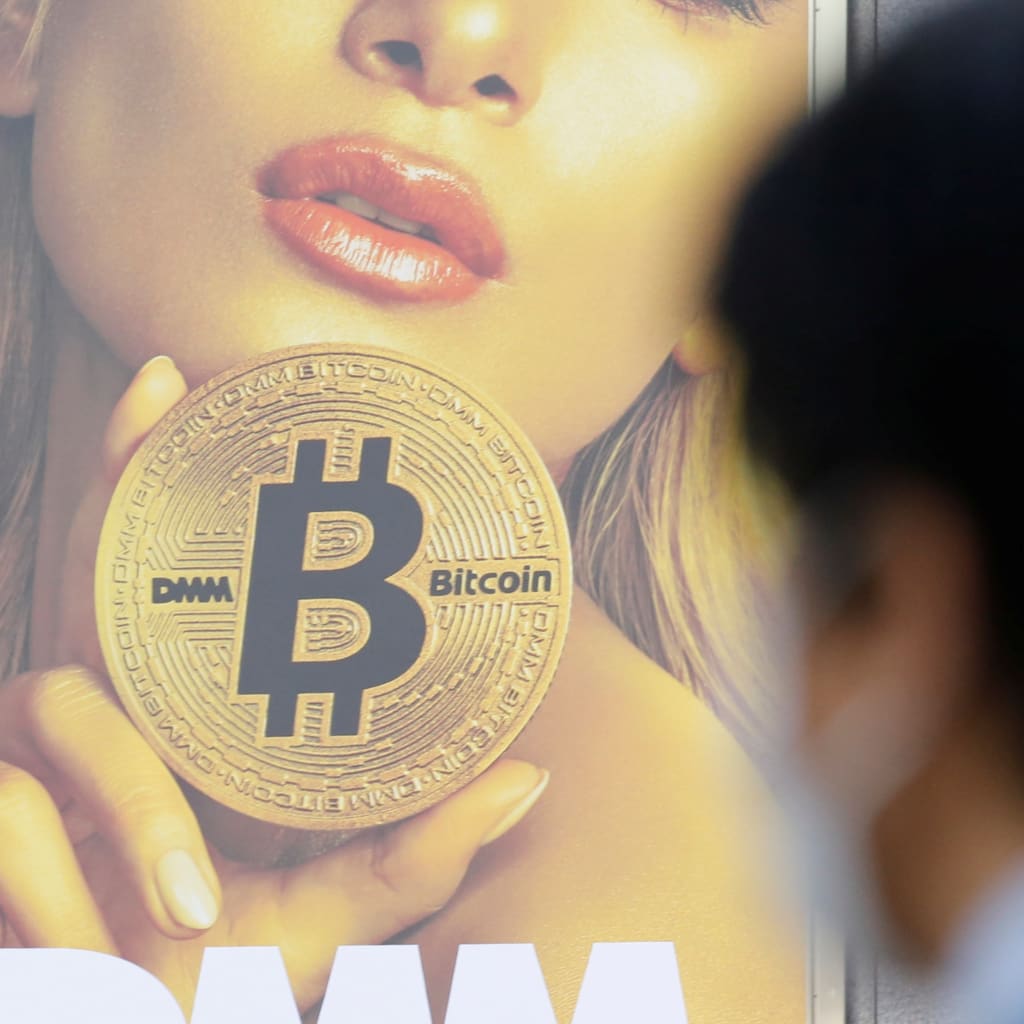<p>A man stands near an advertisement of a cryptocurrency exchange in Tokyo, Japan.</p>
