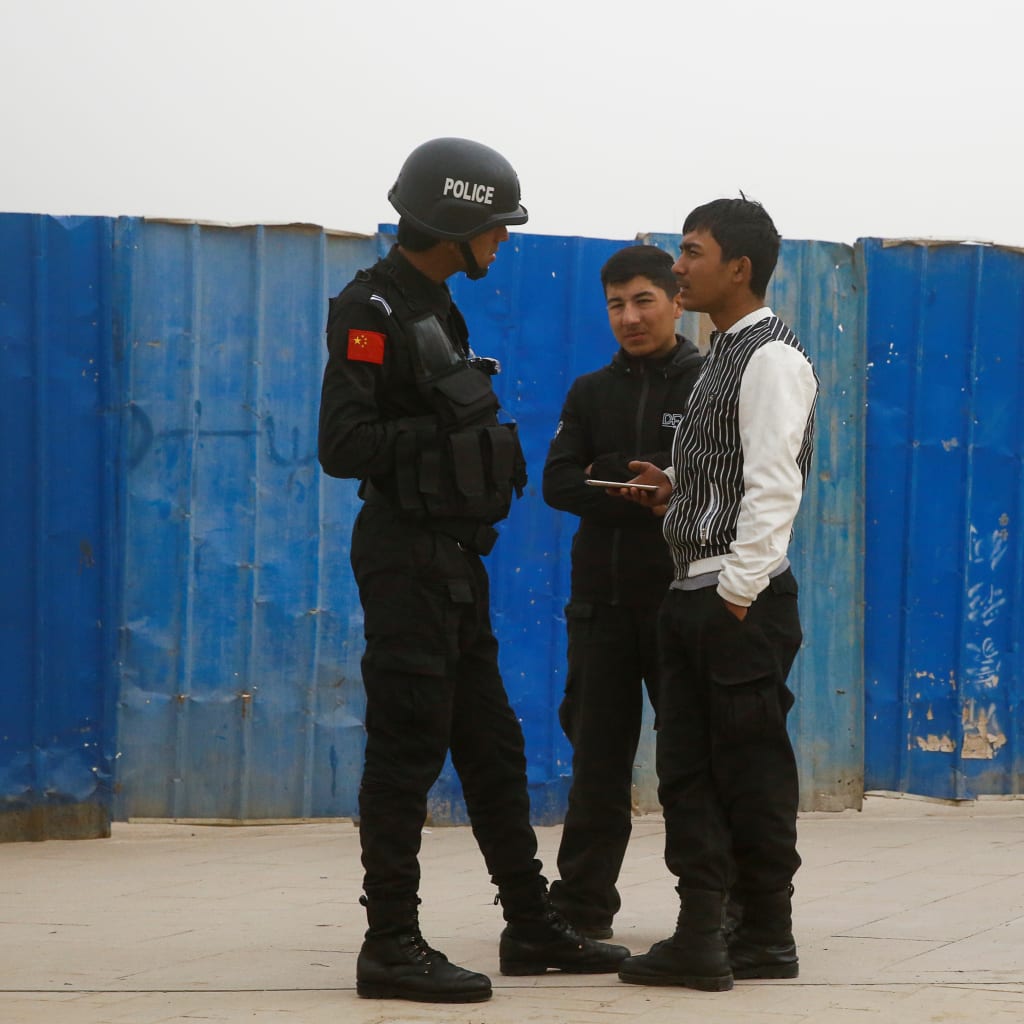 <p>A police officer talks to men in a street in Kashgar, Xinjiang Uighur Autonomous Region, China, March 24, 2017. </p>
