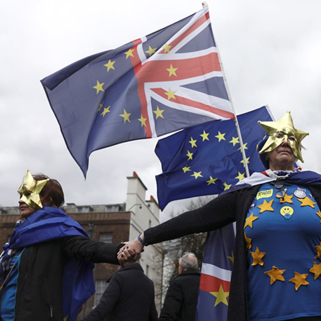 Anti-Brexit protesters wear masks and wave flags during a demonstration in front of the Houses of Parliament in London