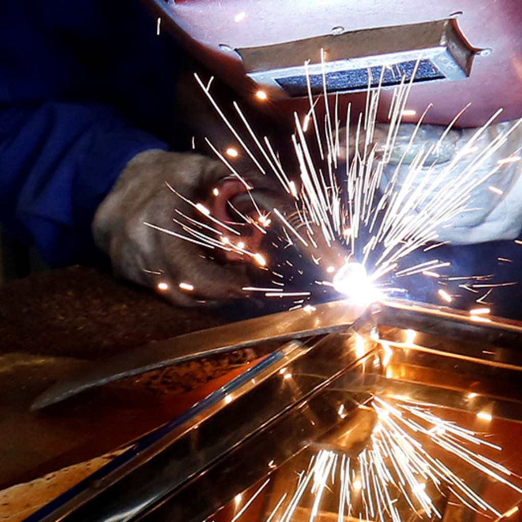 A woman welds a table at Xuan Hoa furniture factory in Xuan Hoa town
