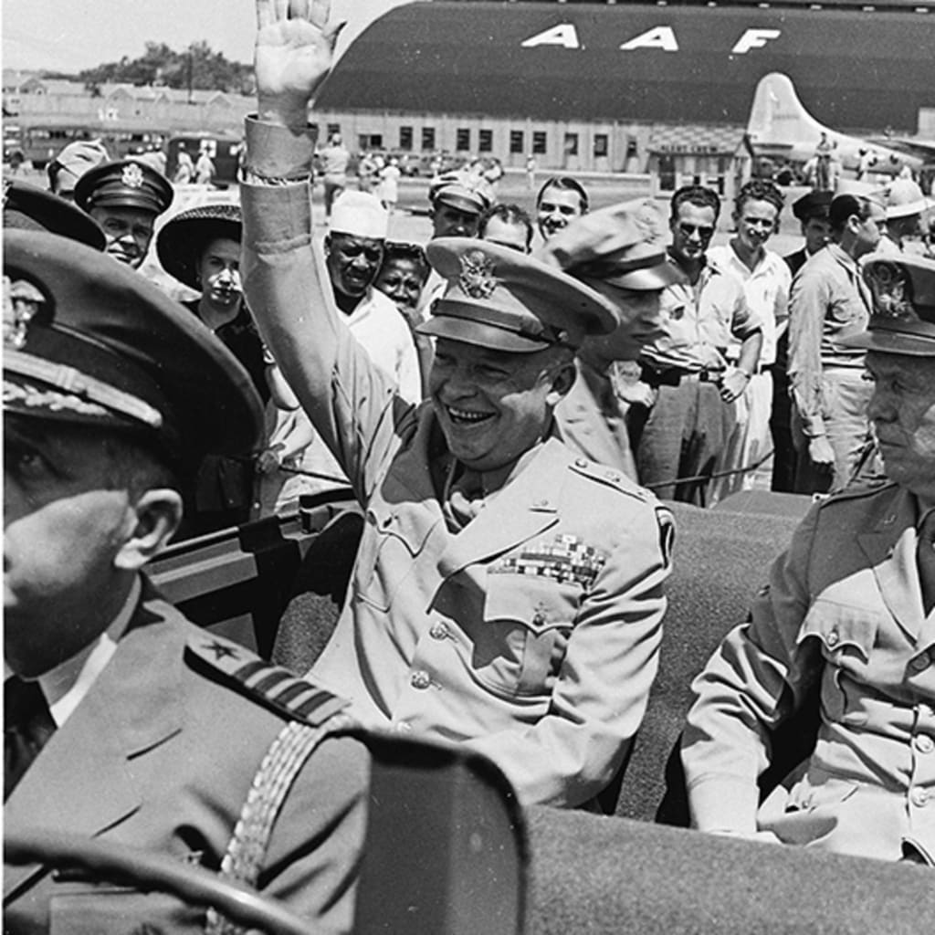 Dwight D. Eisenhower sitting in the back of a jeep with General George C. Marshall