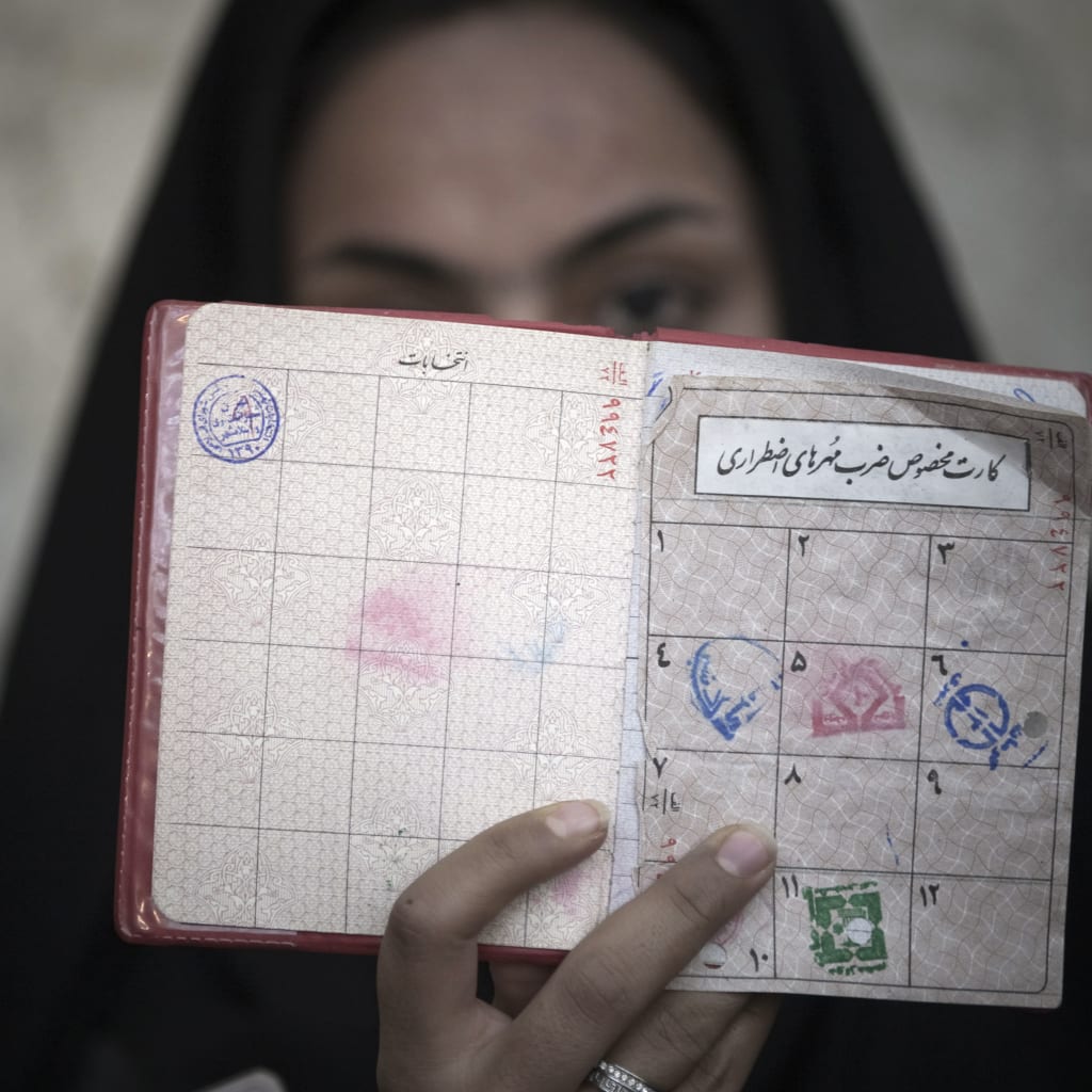 <p>A woman in Iran holds her identification in front of her face after voting March 2, 2012. </p>
