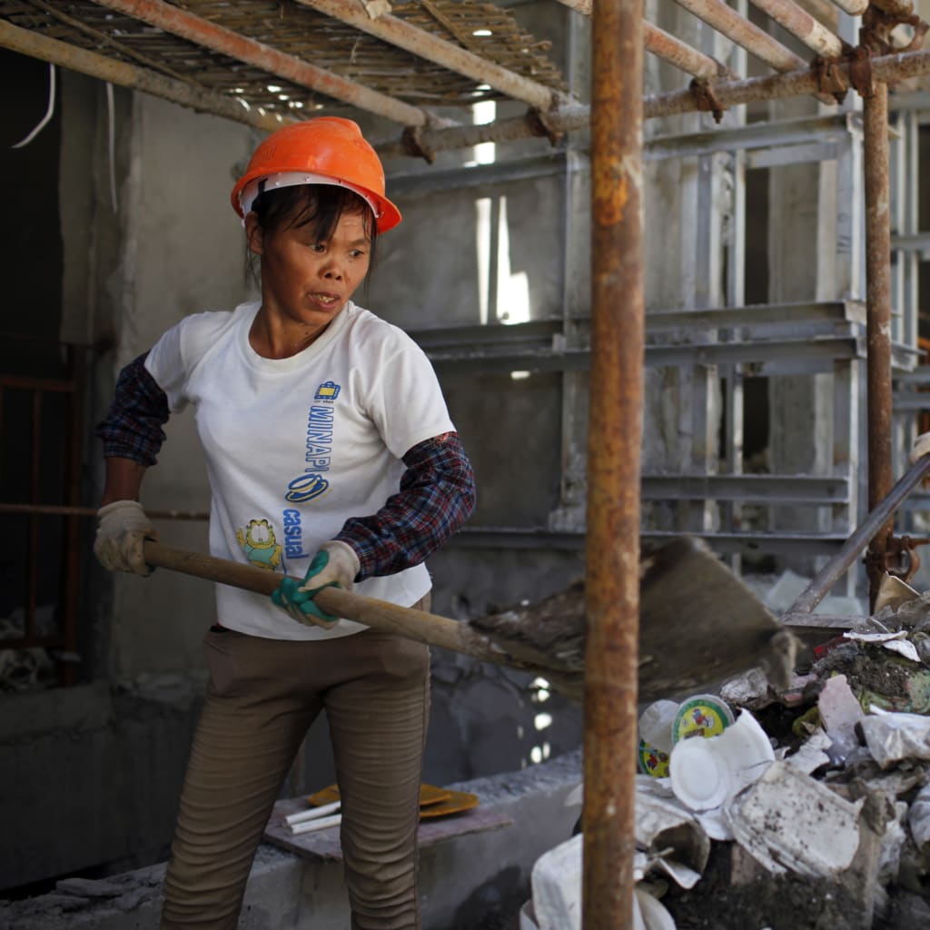 <p>Female migrant construction workers collect garbage onto a cart as they work on a shift at a residential construction site in Shanghai August 12, 2013.</p>
