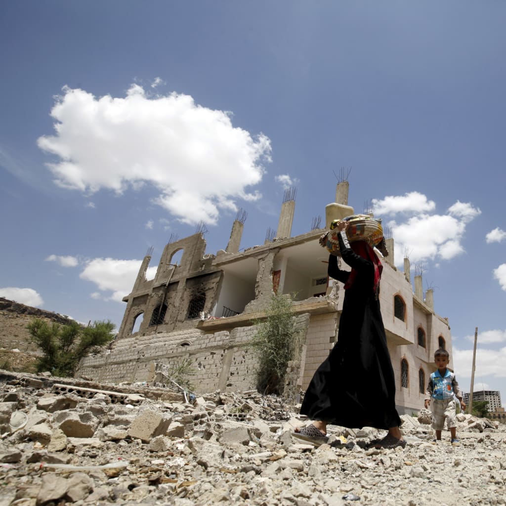 <p>A woman and a boy walk past the ruins of buildings destroyed in Saudi-led air strikes in Yemen’s capital Sanaa. September 13, 2015.</p>
