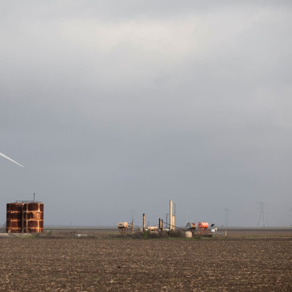 A wind turbine spins next to rusted metal structures in Gregory, Texas, U.S.