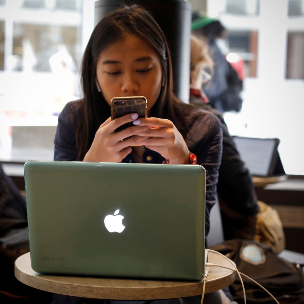 <p>A woman uses her Apple iPhone and laptop in a cafe in lower Manhattan in New York City</p>

