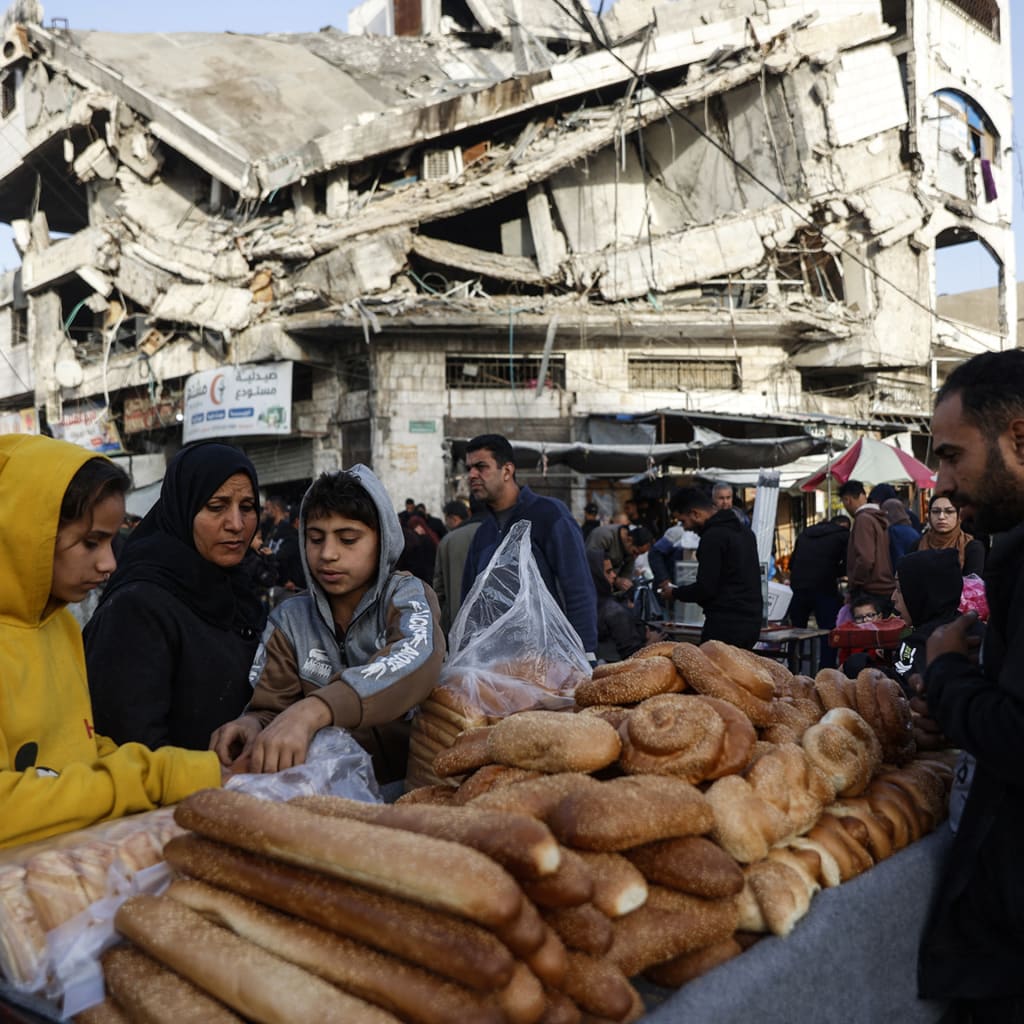 Palestinians sell bread on a street beneath a destroyed building in Gaza City's Zawiya market on February 18, 2026, on the first days of the holy fasting month of Ramadan.