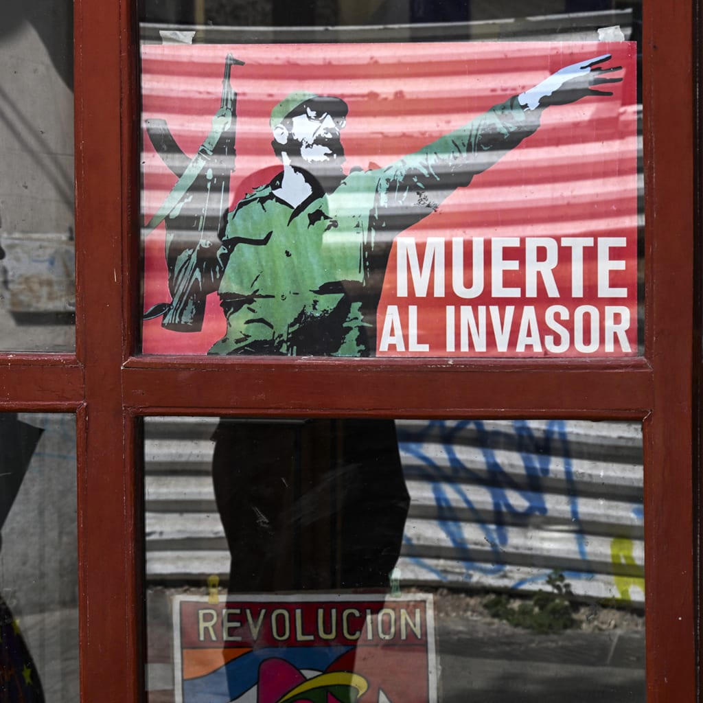 <p>A woman walks past a poster of late Cuban leader Fidel Castro reading, “Death to the invader” in Havana, on March 13, 2026.</p>
