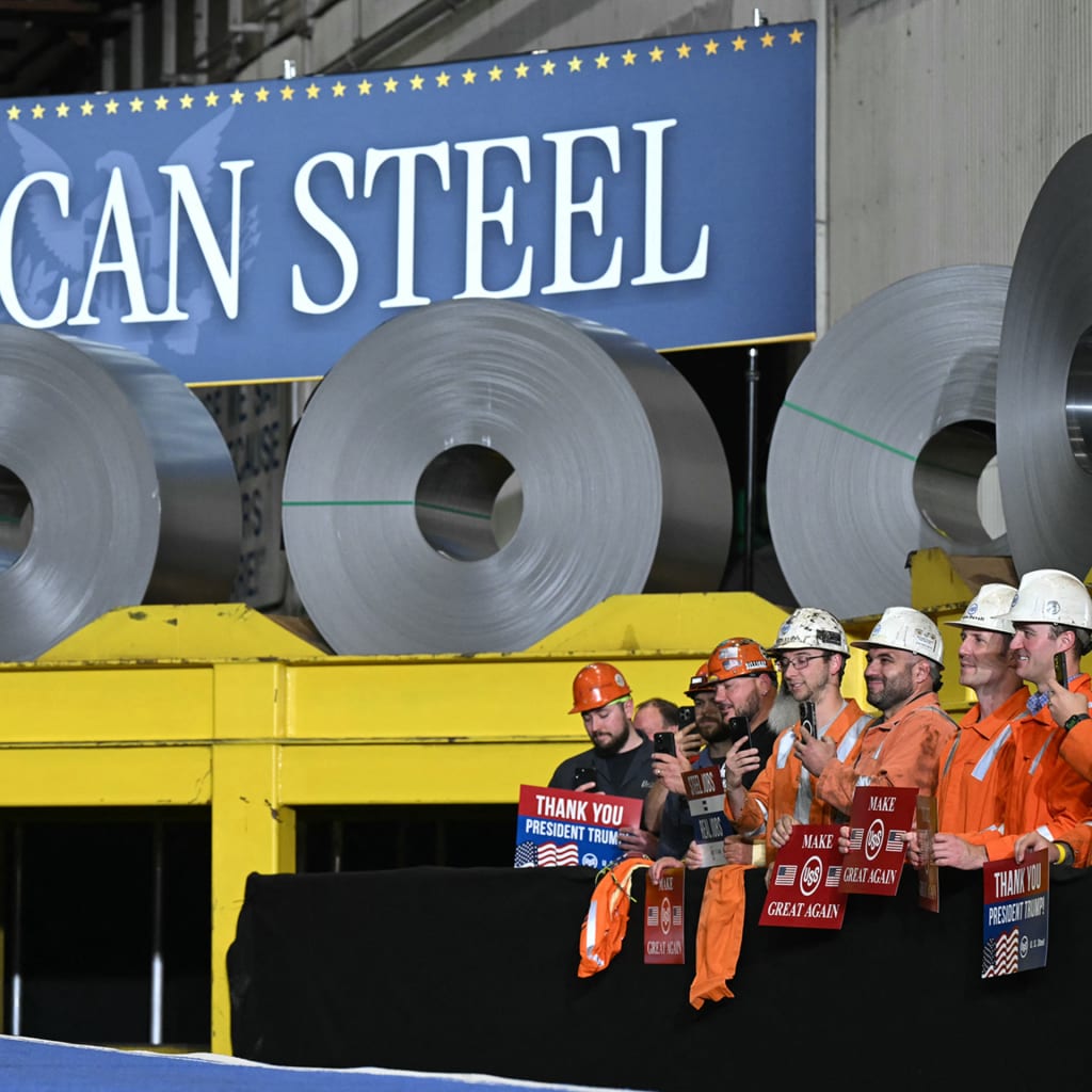 Photo of president trump standing in front of a banner and a pile of steel rolls to mark deal between Nippon Steel and US Steel